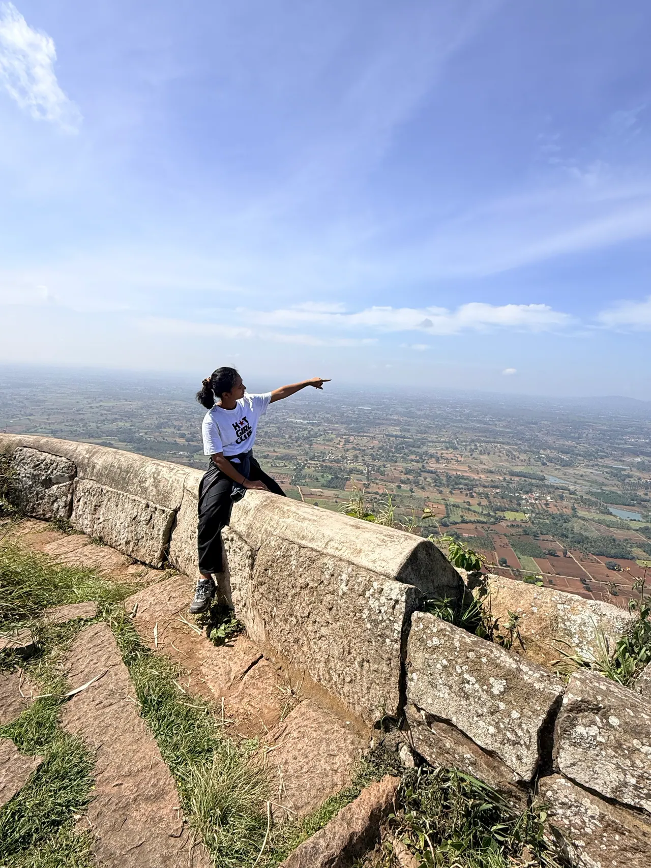 A trekker on the old fort wall pointing across the plains